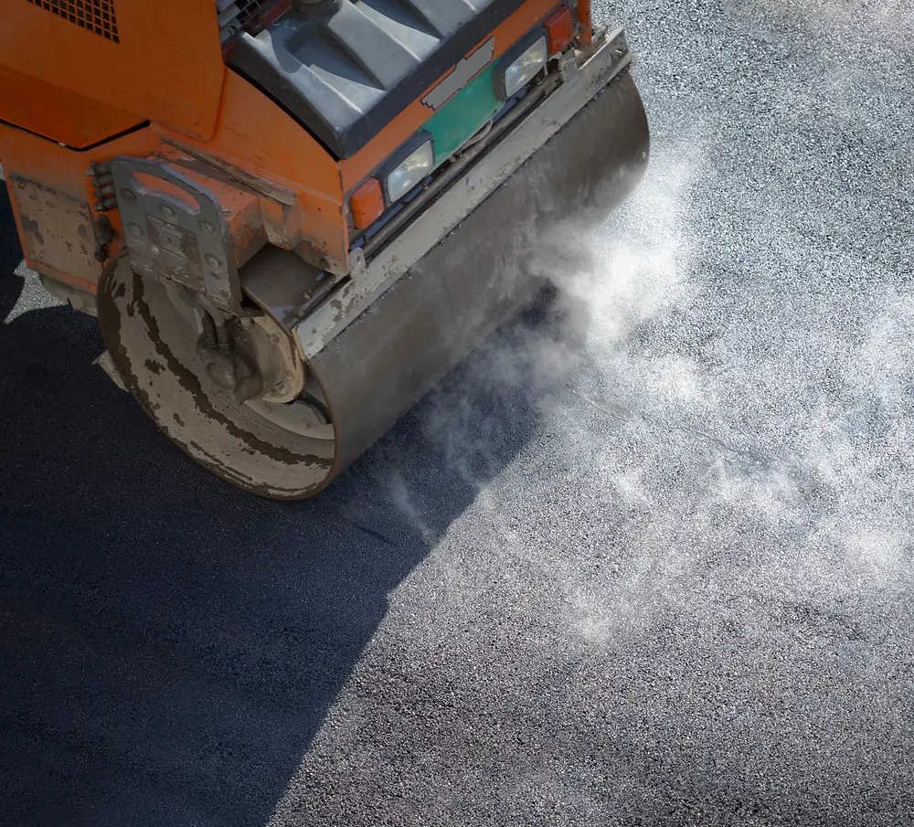 an overhead shot of pavement being flattened by a roller